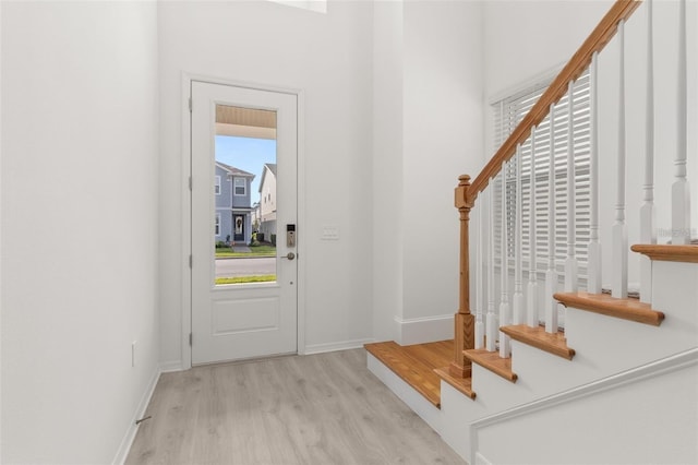 foyer entrance with stairs, wood finished floors, and baseboards