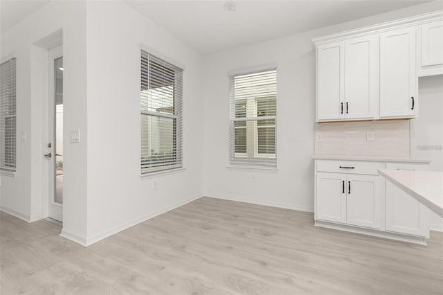 unfurnished dining area featuring light wood-style flooring and baseboards