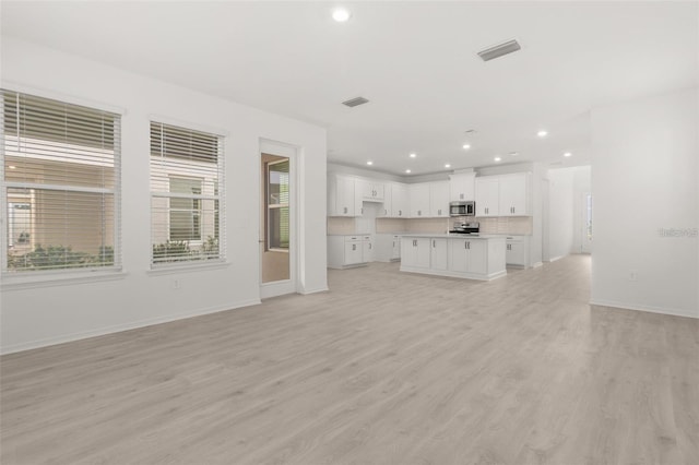 unfurnished living room with recessed lighting, visible vents, baseboards, and light wood finished floors