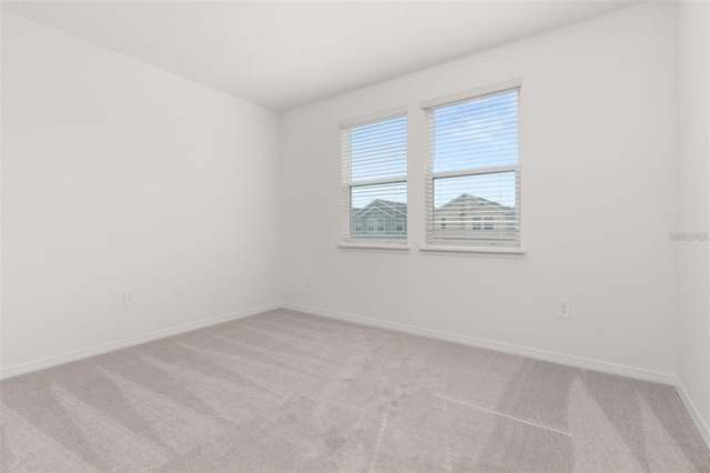 spare room with baseboards and light carpet