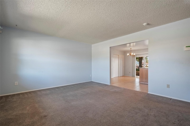 spare room with light tile patterned floors, baseboards, a textured ceiling, light carpet, and a chandelier