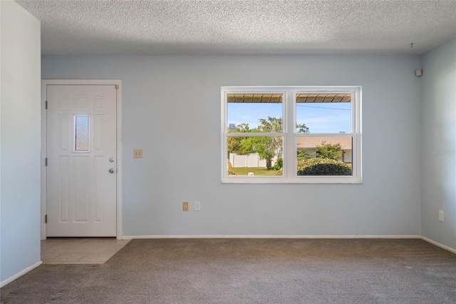 carpeted empty room featuring baseboards and a textured ceiling