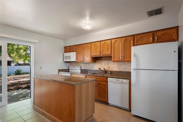 kitchen with dark countertops, visible vents, white appliances, and a sink