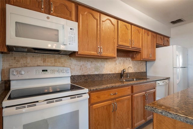 kitchen with visible vents, decorative backsplash, brown cabinets, white appliances, and a sink