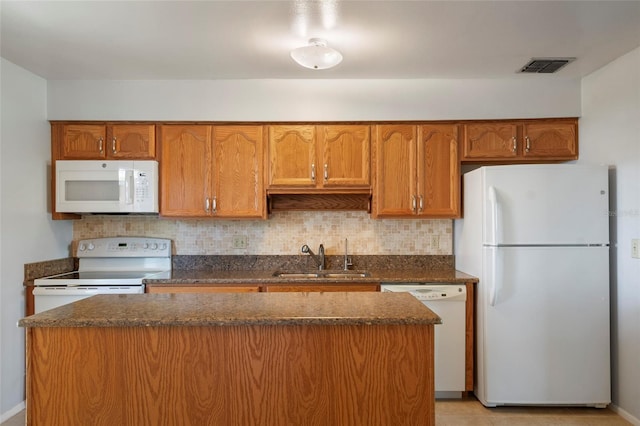 kitchen featuring visible vents, a sink, a kitchen island, tasteful backsplash, and white appliances