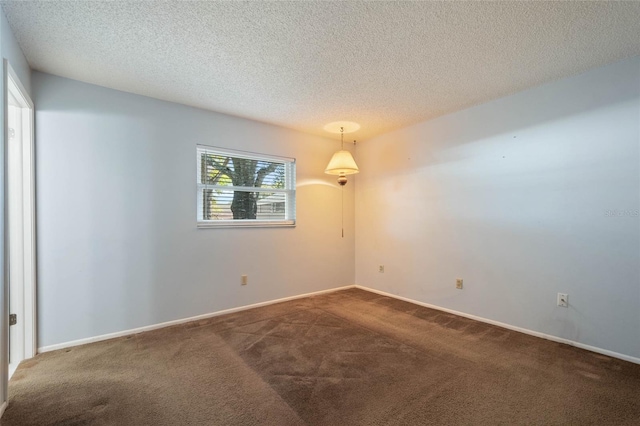 spare room featuring carpet, baseboards, and a textured ceiling