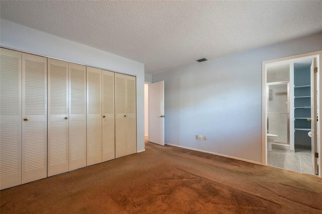 unfurnished bedroom featuring carpet, visible vents, a closet, a textured ceiling, and connected bathroom