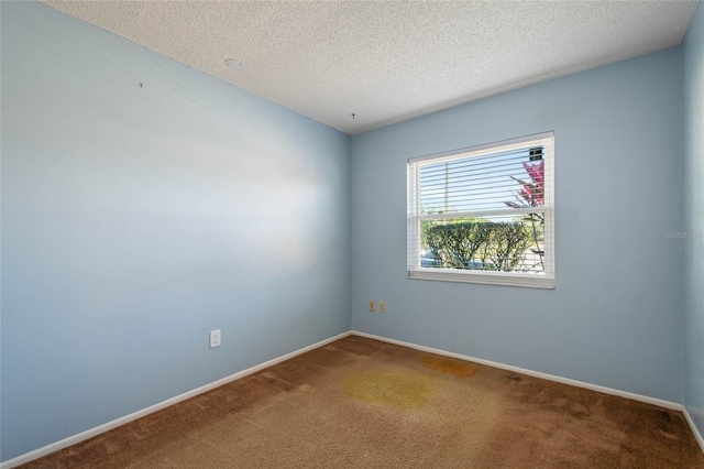 carpeted spare room featuring baseboards and a textured ceiling