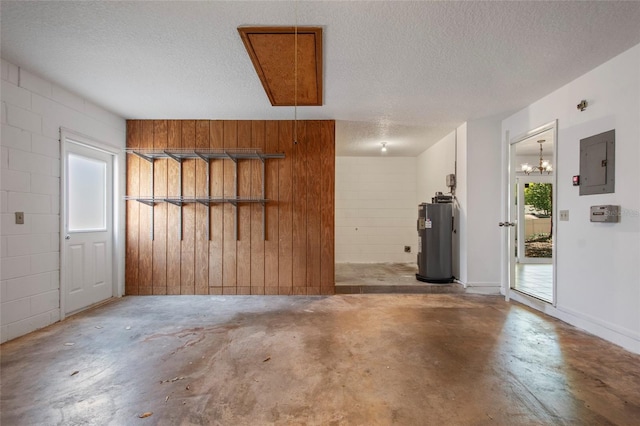 garage featuring concrete block wall, electric panel, and water heater