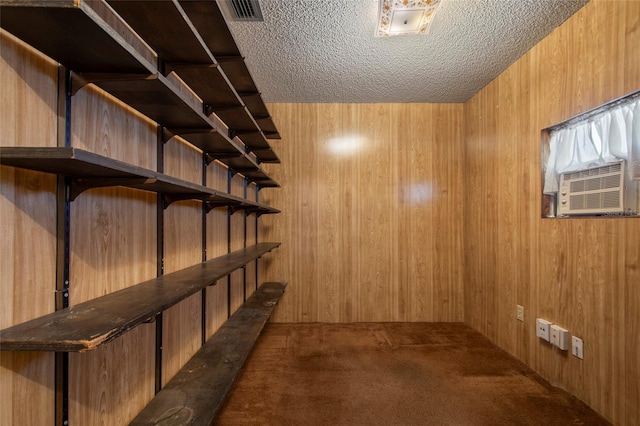 basement with visible vents, a textured ceiling, cooling unit, wooden walls, and carpet flooring