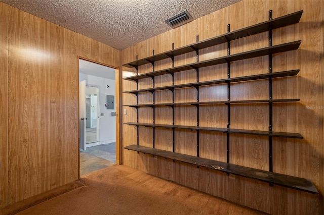 interior space with electric panel, visible vents, wooden walls, and a textured ceiling