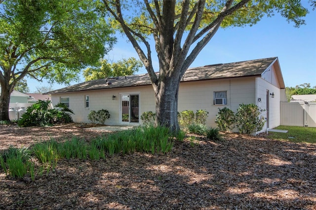 rear view of house with a garage, a patio, concrete block siding, and fence