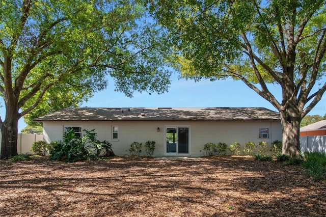 rear view of property with concrete block siding and fence