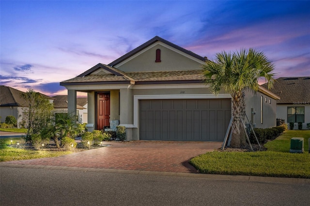 view of front of property featuring cooling unit, stucco siding, an attached garage, and decorative driveway