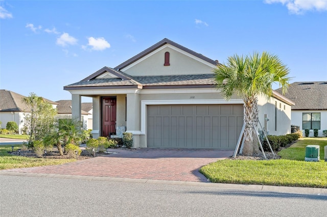 view of front of property featuring stucco siding, a front lawn, decorative driveway, a garage, and central AC unit