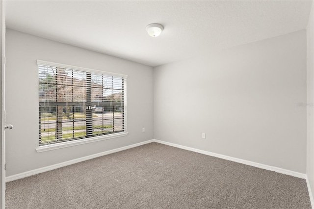 carpeted spare room featuring baseboards