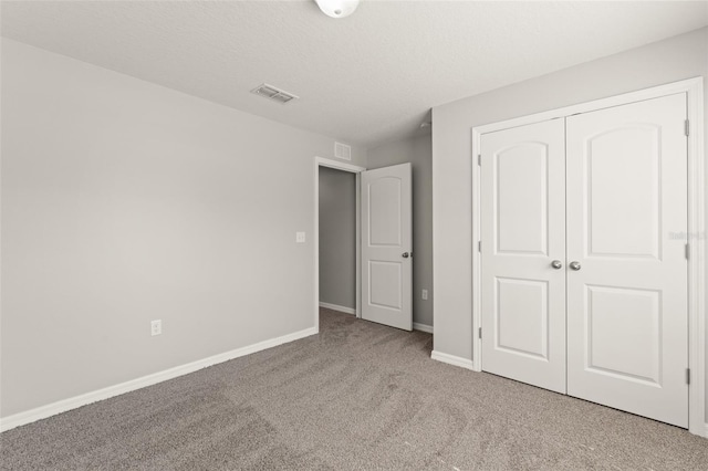 unfurnished bedroom with baseboards, visible vents, a closet, a textured ceiling, and carpet flooring