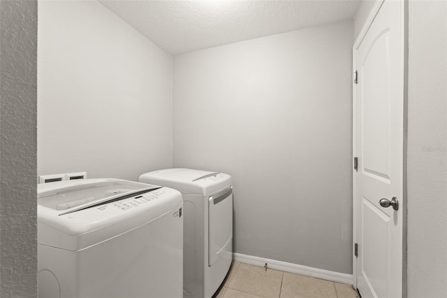 clothes washing area featuring independent washer and dryer, a textured ceiling, light tile patterned flooring, baseboards, and laundry area