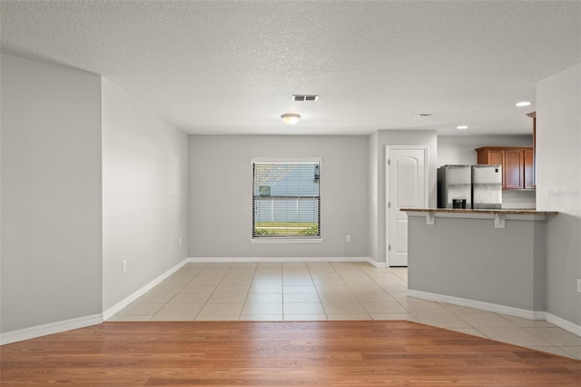 unfurnished living room with visible vents, baseboards, light tile patterned floors, recessed lighting, and a textured ceiling