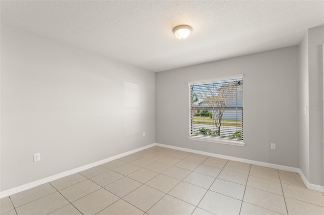 unfurnished room featuring baseboards, a textured ceiling, and light tile patterned flooring