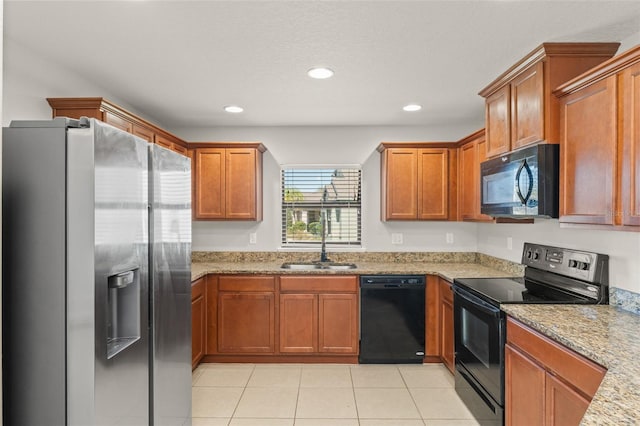 kitchen with a sink, black appliances, light tile patterned flooring, and brown cabinetry