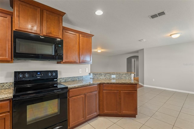 kitchen with visible vents, brown cabinetry, a peninsula, arched walkways, and black appliances