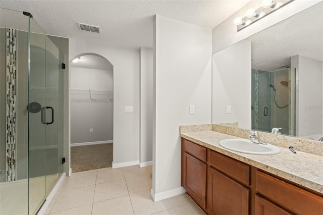 full bath featuring tile patterned floors, visible vents, a stall shower, a textured ceiling, and vanity