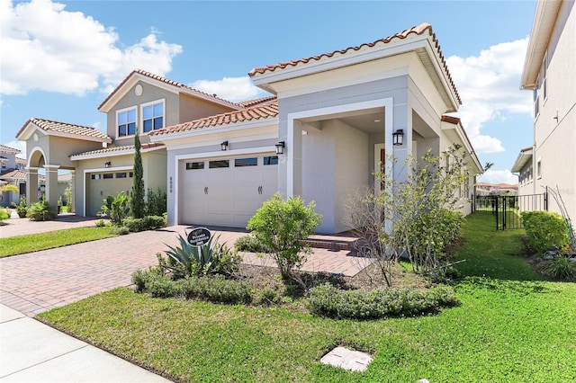 mediterranean / spanish-style house with stucco siding, a tiled roof, decorative driveway, and a front lawn