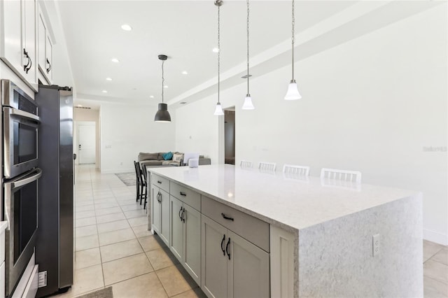 kitchen featuring light tile patterned floors, recessed lighting, appliances with stainless steel finishes, open floor plan, and a center island