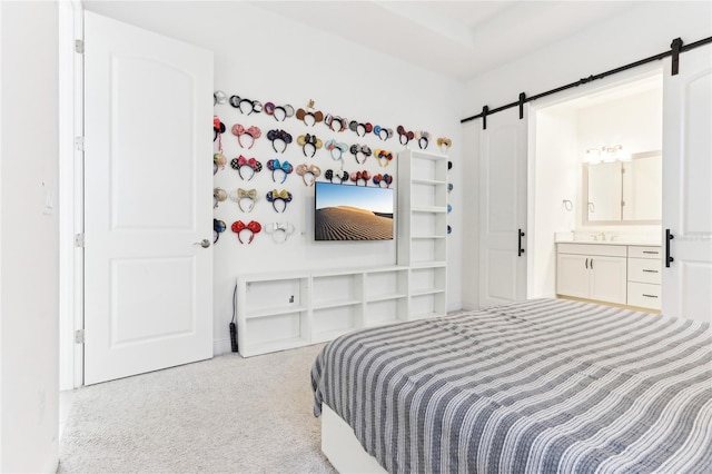 carpeted bedroom featuring connected bathroom and a barn door