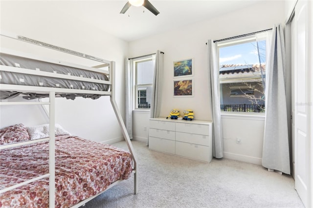 bedroom featuring light colored carpet, a ceiling fan, and baseboards