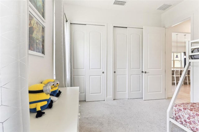 bedroom with visible vents, multiple closets, and carpet floors