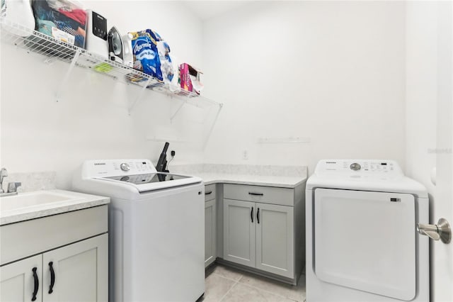 washroom with a sink, light tile patterned floors, cabinet space, and washing machine and clothes dryer