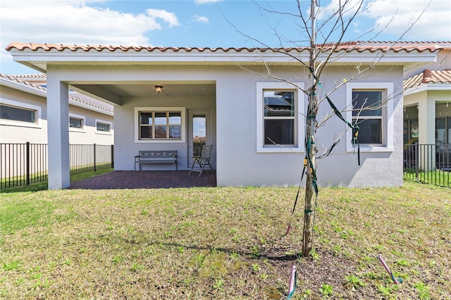 back of house with stucco siding, a yard, a tile roof, and fence