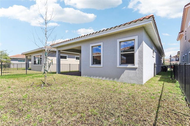 rear view of property with stucco siding, a lawn, a fenced backyard, and a tiled roof