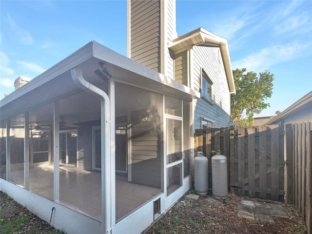 view of home's exterior with fence, a sunroom, and a chimney