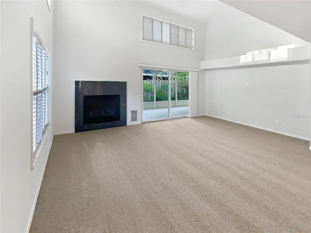 unfurnished living room with a fireplace, baseboards, a towering ceiling, and carpet floors