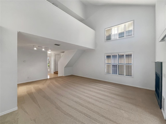 unfurnished living room featuring baseboards, a fireplace, high vaulted ceiling, and carpet