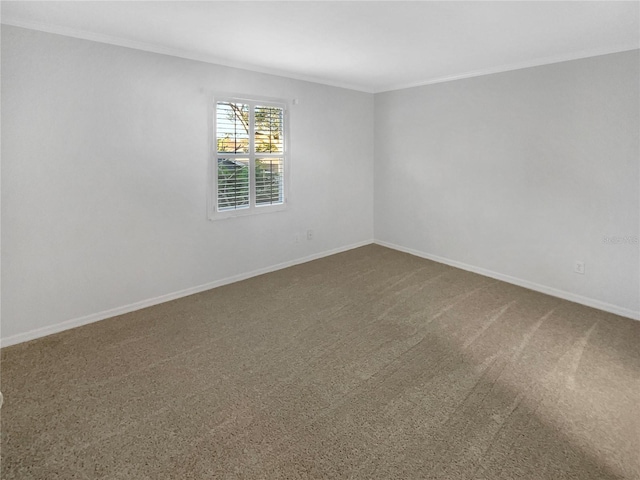 carpeted empty room featuring baseboards and crown molding