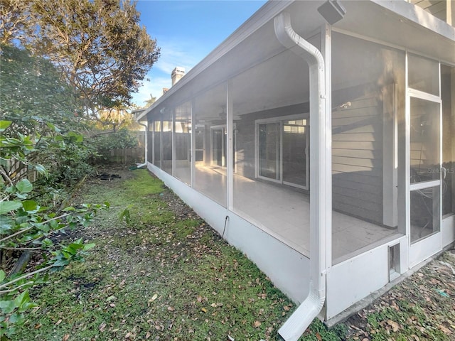 view of side of property featuring fence and a sunroom