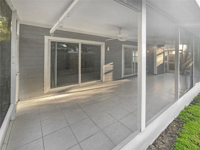 unfurnished sunroom featuring a ceiling fan