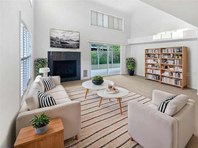 carpeted living room featuring a healthy amount of sunlight, a towering ceiling, and a fireplace