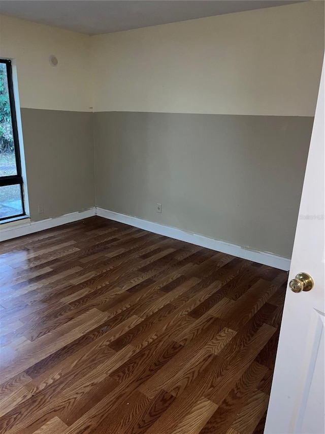 unfurnished room with dark wood-type flooring and baseboards