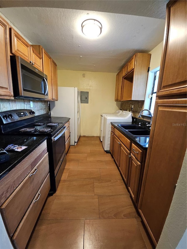 kitchen with separate washer and dryer, a sink, decorative backsplash, electric range oven, and stainless steel microwave