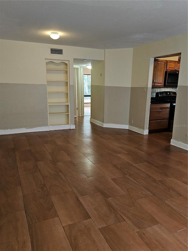 unfurnished room with visible vents, built in shelves, and baseboards