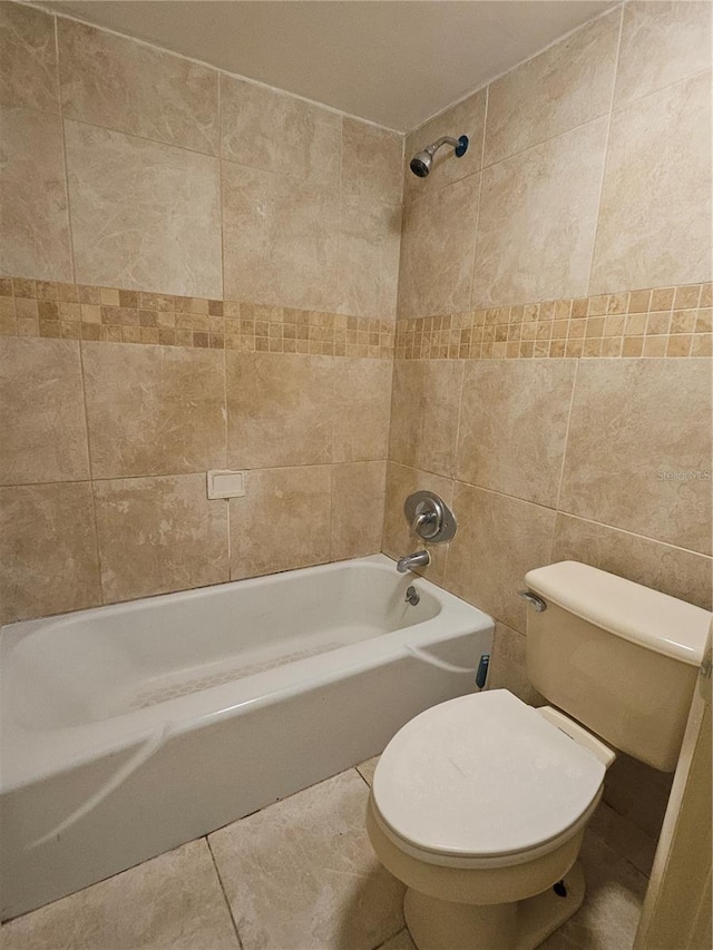 bathroom with shower / bathing tub combination, toilet, tile walls, and tile patterned flooring