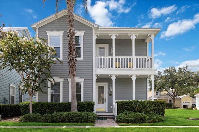 view of front facade with a balcony, a porch, and a front lawn