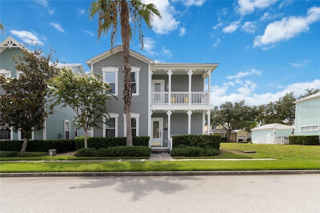 italianate-style house featuring a balcony and a front lawn