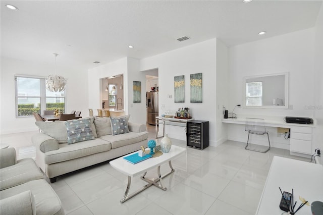 living room with a notable chandelier, recessed lighting, beverage cooler, and visible vents