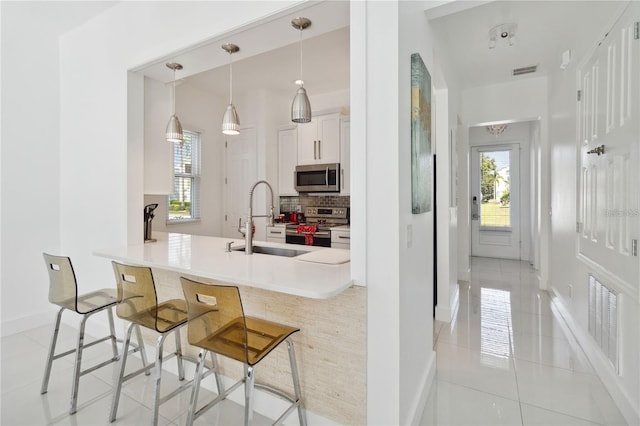 kitchen with visible vents, backsplash, a kitchen breakfast bar, stainless steel appliances, and a sink